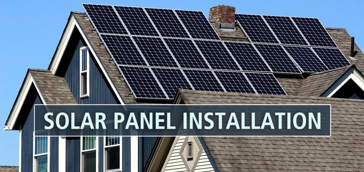 Solar Panel Installation. Side view of a blue house with rows of solar panels installed along the roof.