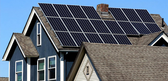 Side view of a blue house with rows of solar panels installed along the roof.